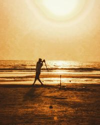 Silhouette man standing on beach against sky during sunset