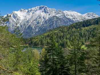 Scenic view of snowcapped karwendel  mountains and lake lautersee against sky in spring