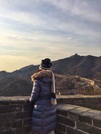 Rear view of woman standing on mountain against sky