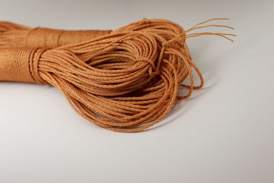 Close-up of rope on table against white background