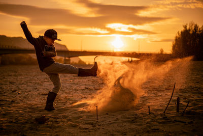 Man on beach against sky during sunset