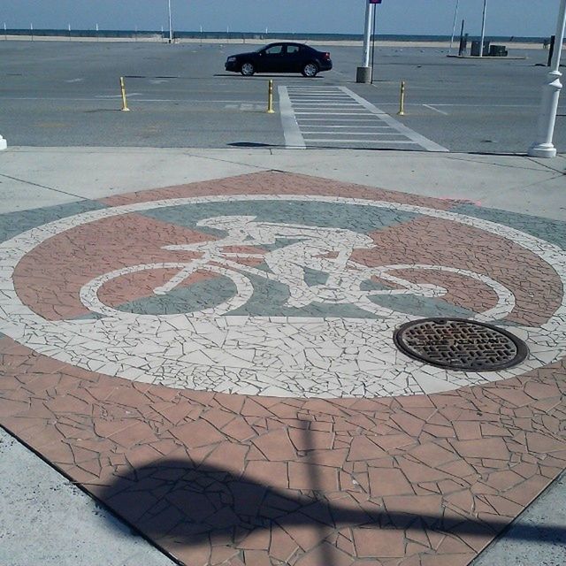 street, high angle view, road marking, shadow, road, sunlight, transportation, communication, sidewalk, paving stone, outdoors, asphalt, day, cobblestone, creativity, city, arrow symbol, sign, footpath, art