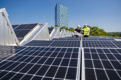 Two technicians strategizing on the rooftop of a corporate building equipped with solar panels