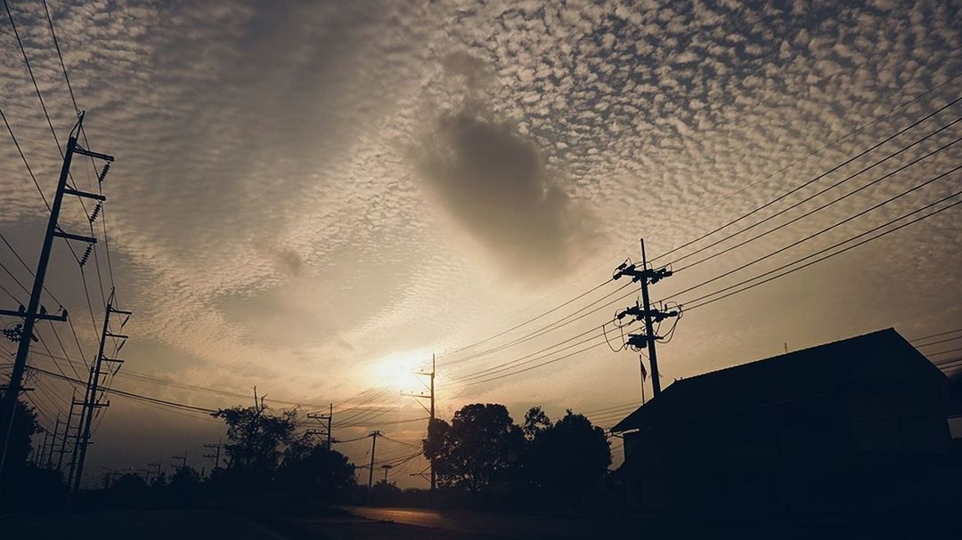 LOW ANGLE VIEW OF SILHOUETTE ELECTRICITY PYLON AND BUILDINGS AGAINST SKY