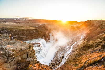 Scenic view of waterfall against sky during sunset