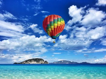 Hot air balloon flying over sea against sky