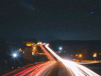 Light trails on street against sky at night