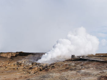 Smoke emitting from volcanic land against clear sky