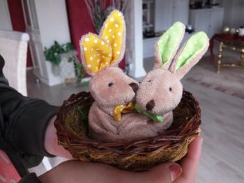 Close-up of hand holding nest with stuffed toy easter bunnies