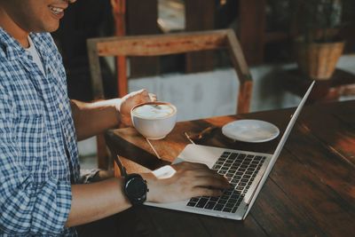 Midsection of woman using laptop at table