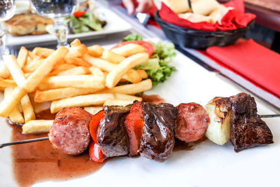 Close-up of beef skewer by french fries in plate