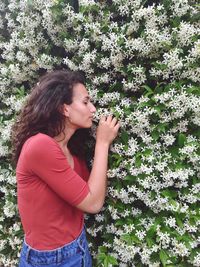 Beautiful young woman standing by flowering plants