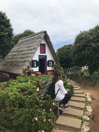 Rear view of woman by plants against building