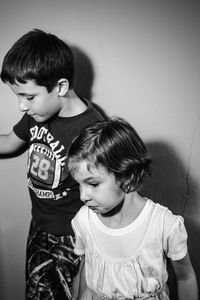 Siblings standing against wall at home