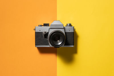 Retro analogue camera. vintage old fashioned camera with lens on two colored background. top view.