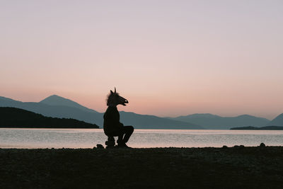 Silhouette man on beach against sky during sunset