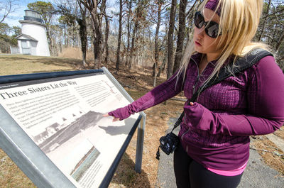 Midsection of woman holding pink while standing by tree