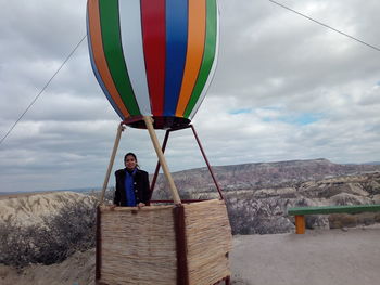 Man standing on multi colored umbrella by sea against sky