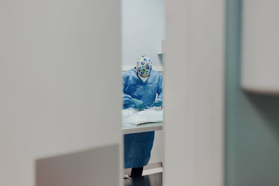 Focused male veterinarian in uniform and respiratory mask using medical instruments during surgery in hospital