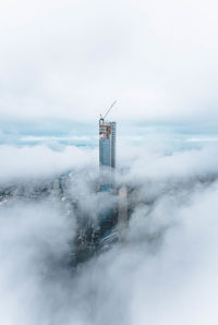 Lighthouse amidst buildings and sea against sky