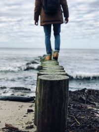 Low section of man standing on wooden post