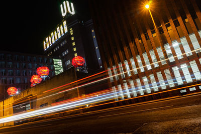 Light trails on road amidst buildings in city at night