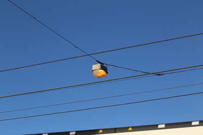 Low angle view of light bulbs hanging against clear sky