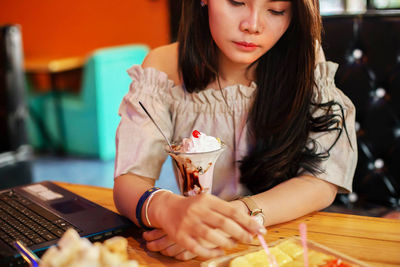 Young woman using mobile phone while sitting on table