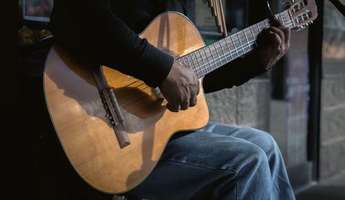 Low section of man holding guitar