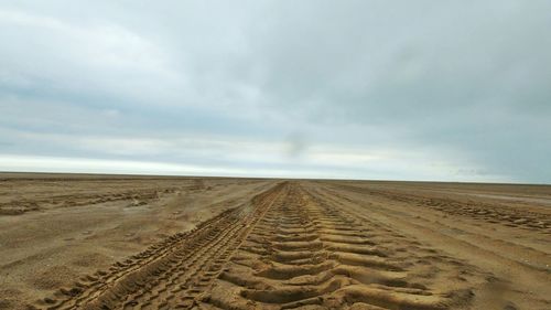 Scenic view of desert against cloudy sky