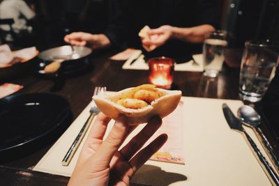 Cropped hand holding stuffed food at table in restaurant during christmas