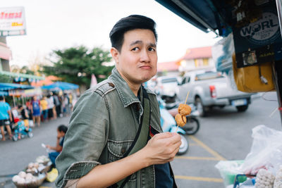 Portrait of young man standing on street in city