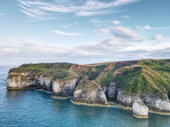 Scenic view of rocks by sea against sky