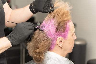 An elderly woman in a beauty salon dyes her hair