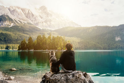 Rear view of woman and dog looking at lake