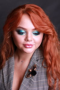 Close-up of sensuous young woman looking down against black background