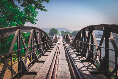 Footbridge over railroad tracks against sky