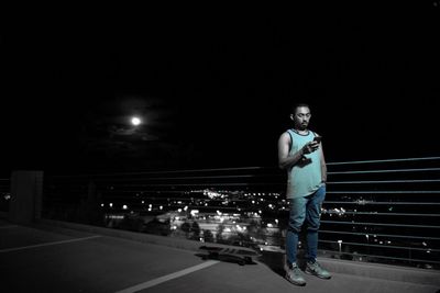 Portrait of young man standing on road at night