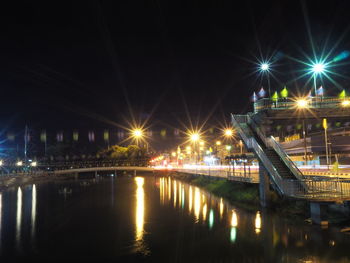 Illuminated bridge over river against sky at night