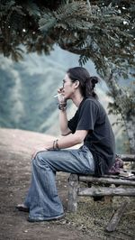 Side view of a young woman sitting outdoors