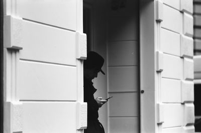 Man using phone while standing by building in city