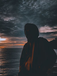 Man standing by sea against sky during sunset