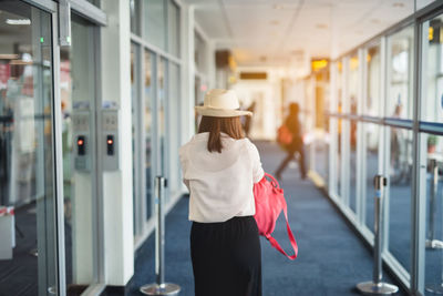 Rear view of young woman walking in corridor at airport