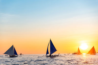 Sailboat sailing on sea against sky during sunset