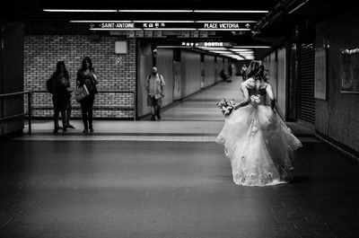 Rear view of bride walking at underground subway station