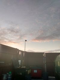 Cars on street by buildings against sky during sunset