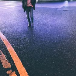 Low section of man walking on wet road