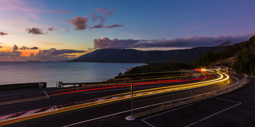 Light trails on road against sky at night