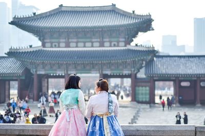 Rear view of people walking outside temple against buildings