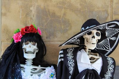 Skeletons in traditional clothing against wall